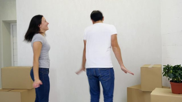 Couple is having fun dacing comically and laughing in their new appartment.