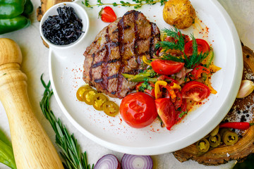 BBQ, juicy steak with grilled vegetables and sauce on a white plate