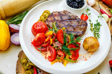 BBQ, juicy steak with grilled vegetables and sauce on a white plate