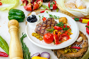 BBQ, juicy steak with grilled vegetables and sauce on a white plate