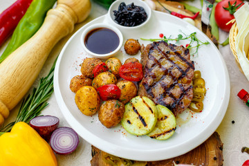 BBQ, juicy steak with grilled vegetables and sauce on a white plate