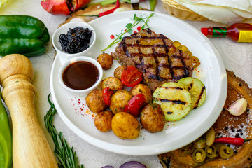 BBQ, juicy steak with grilled vegetables and sauce on a white plate