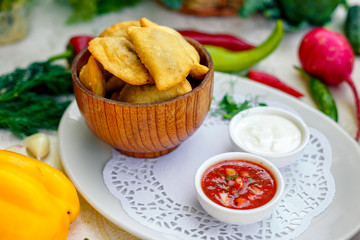 pies with meat in wooden utensils with sauces on a white plate