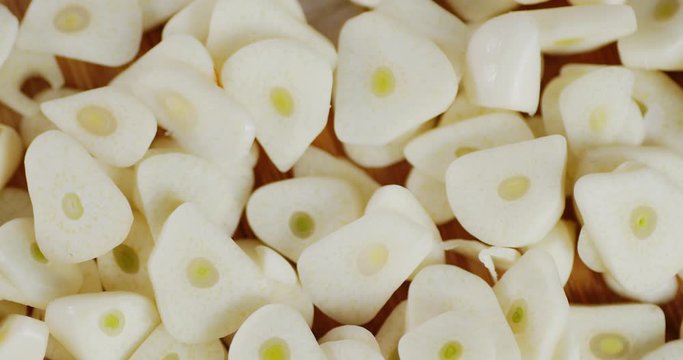Slices of fresh garlic slowly rotate.