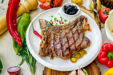 steak entrecote with pickled onions and jalapeno pepper on a white plate