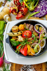 fried meat on the frying pan with vegetables and baked potatoes with vegetables