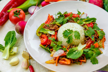 Thai meat with vegetables on a decorated table in a white plate