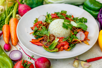 Thai meat with vegetables on a decorated table in a white plate
