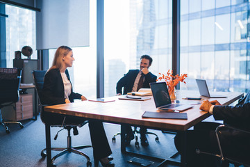 Successful professional experts in elegant wear discussing productive plan for work of employees during business meeting in conference room, concept of corporate brainstorming and collaboration