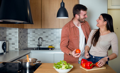 Joyful couple cooking together in kitchen