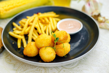 Cheese balls with crispy fresh French fries with sauce on a decorated table