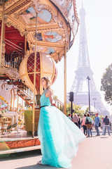 Beautiful young girl strolling through Paris next to the carousel, vintage atmosphere