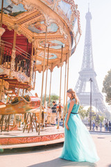 Beautiful young girl strolling through Paris next to the carousel, vintage atmosphere