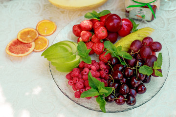 berries and fruit in a transparent plate. Apples, pears, cherries, raspberries, plums, grapes.