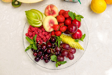 berries and fruit in a transparent plate. Apples, pears, cherries, raspberries, plums, grapes.