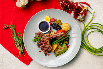 Grilled meat with vegetables and sauce on a white plate