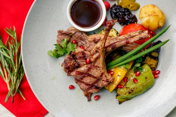 Grilled meat with vegetables and sauce on a white plate