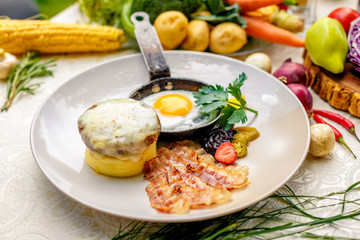 breakfast, fried egg in a frying pan with tender slices of bacon and mashed potatoes with cheese