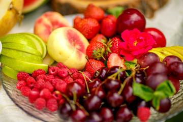 berries and fruit in a transparent plate. Apples, pears, cherries, raspberries, plums, grapes.