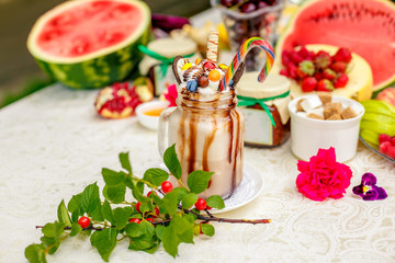 Crazy shake on top with marshmallow, waffles, biscuits and sweets on a bright colored background
