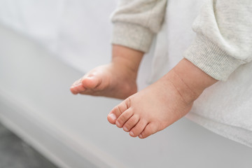 Asian baby sitting on bay window with feet closeup