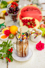 Crazy shake on top with marshmallow, waffles, biscuits and sweets on a bright colored background