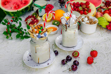 Crazy shake top with marshmallow, waffles, slices of banana and sweets on a bright colored background