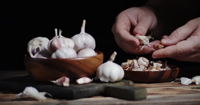 Men hands peel garlic from the skin.