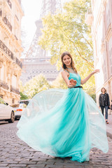 Beautiful young girl in a dress on the street with a view of the Eiffel tower
