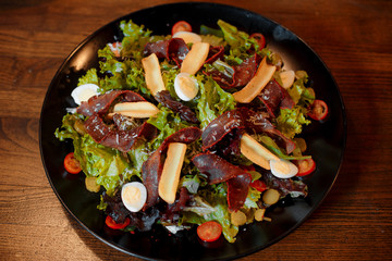 salad with eggs and jerky with fresh vegetables on a wooden table