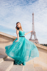 Fototapeta premium a girl in Paris in a green dress against the backdrop of the Eiffel tower elegant on the Trocadero square in summer a luxurious beautiful figure