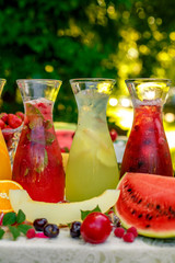 fresh lemonade collection (watermelon, orange, lemon, strawberry and berry) in the street, on a wooden table with fruit