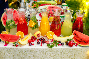 fresh lemonade collection (watermelon, orange, lemon, strawberry and berry) in the street, on a wooden table with fruit