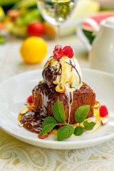 chocolate sponge cake with ice cream and fruit on a served table