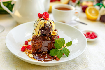 chocolate sponge cake with ice cream and fruit on a served table