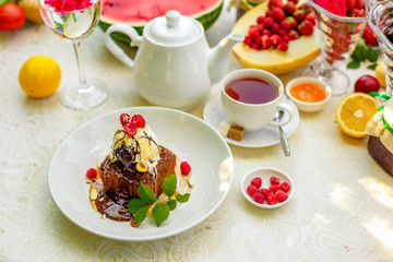 chocolate sponge cake with ice cream and fruit on a served table