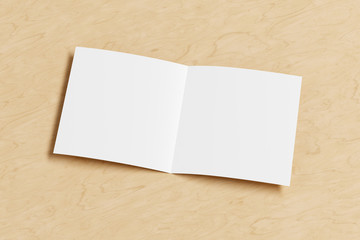 Blank square pages leaflet on wooden background. Bi-fold or half-fold opened brochure isolated with clipping path. Side view. 3d illustration