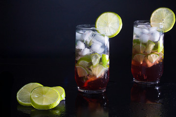 Campari drink with gin with ice and lemon on black background