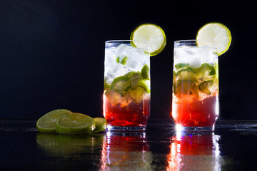 Campari drink with gin with ice and lemon on black background