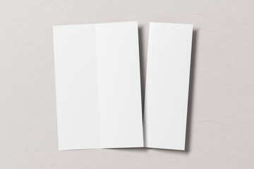 Blank vertical A4 leaflet on white wooden background. Bi-fold or half-fold opened and folded brochure isolated with clipping path. View directly above. 3d illustration