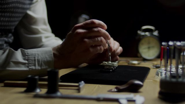 watchmaker repairs an old clock close up