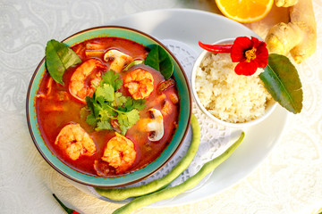 Thai soup tom yam with seafood (octopus, shrimps), herbs and vegetables served on the table with ingredients, healthy food