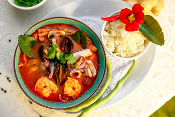 Thai soup tom yam with seafood (octopus, shrimps), herbs and vegetables served on the table with ingredients, healthy food