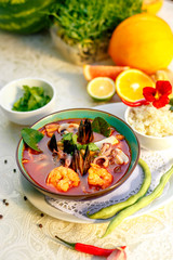 Thai soup tom yam with seafood (octopus, shrimps), herbs and vegetables served on the table with ingredients, healthy food