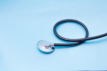 Black Stethoscope isolated on blue background, top view. Medical tool
