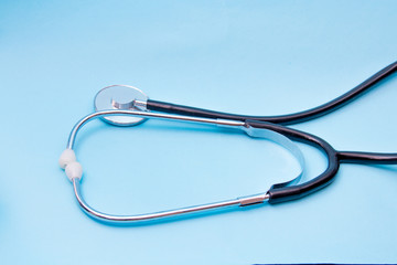 Black Stethoscope isolated on blue background, top view. Medical tool