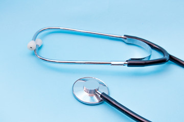 Black Stethoscope isolated on blue background, top view. Medical tool
