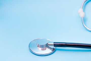Black Stethoscope isolated on blue background, top view. Medical tool