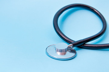 Black Stethoscope isolated on blue background, top view. Medical tool