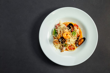 delicious Italian pasta with cheese and seafood (mussels, shrimps) on a white plate, isolated